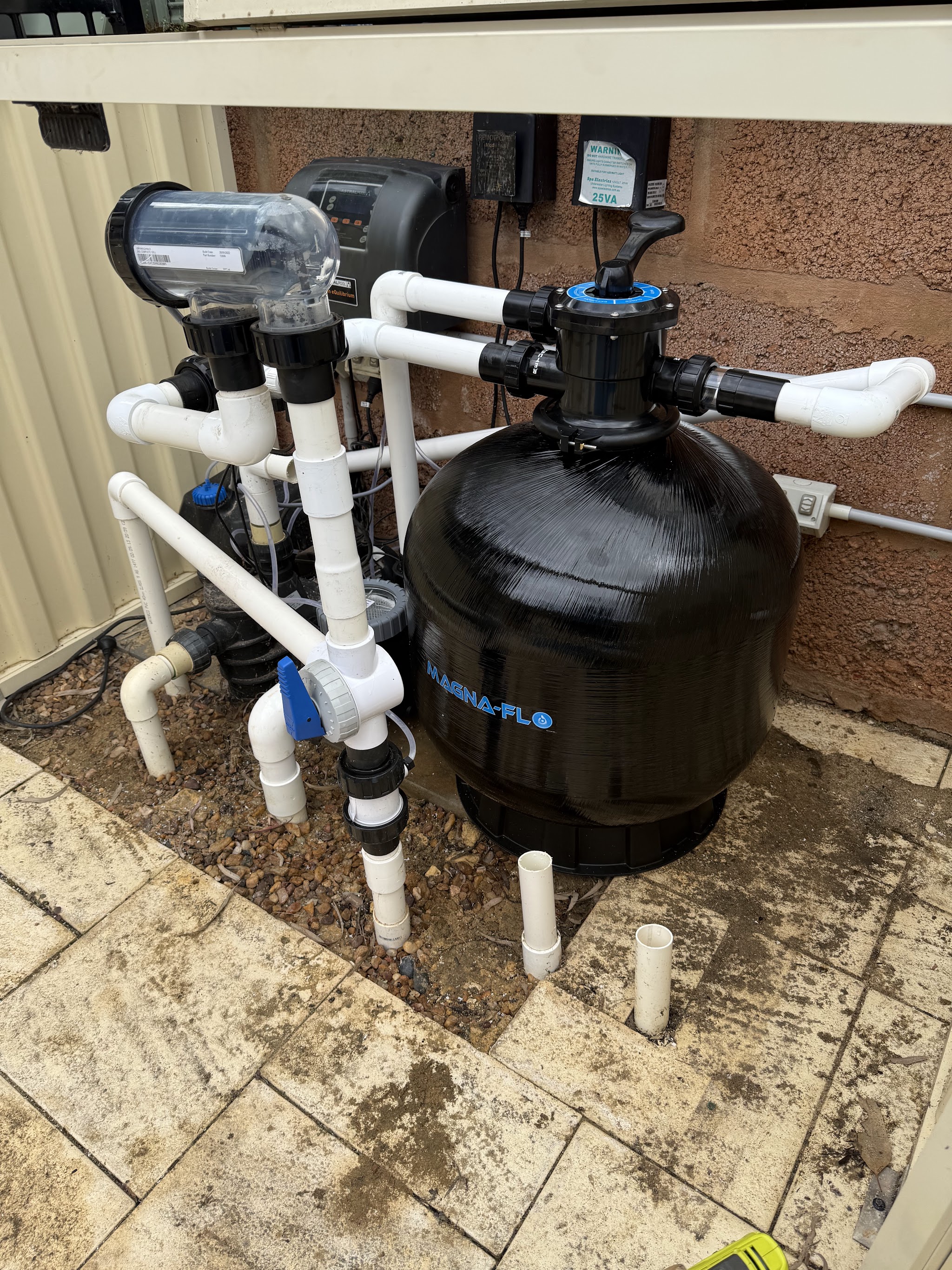 A new Magna-Flo sand filter and plumbing installed against a rendered wall