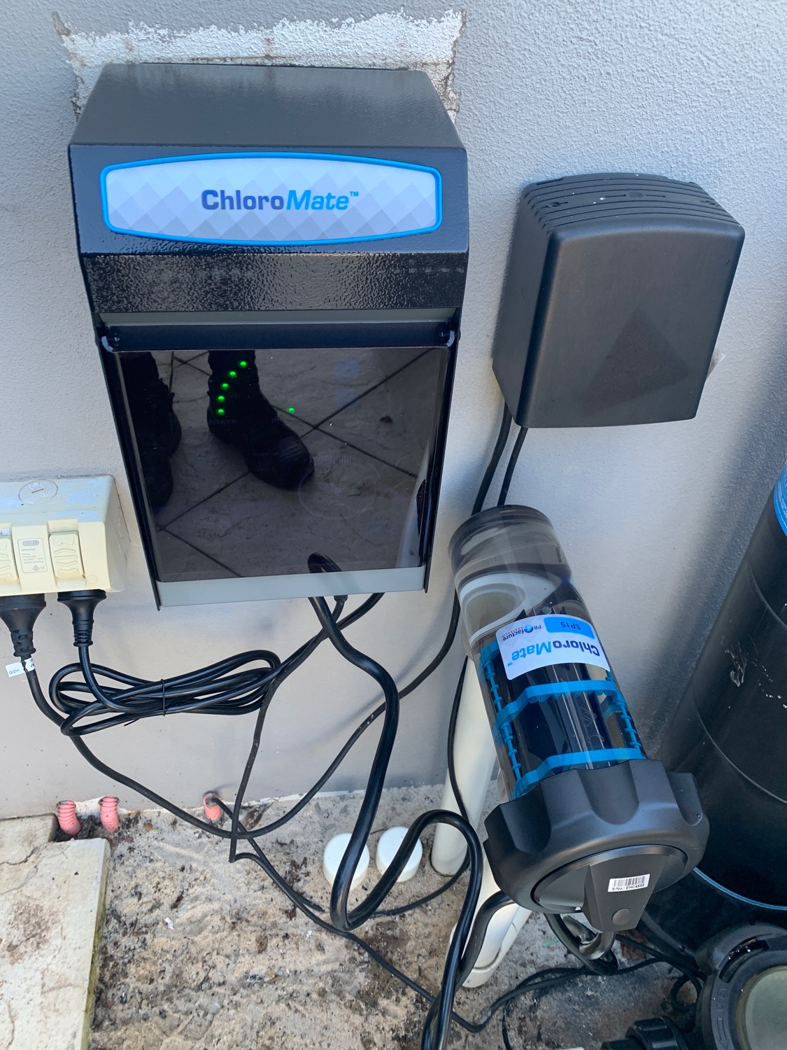 A ChloroMate salt water chlorinator mounted on a wall with its cell below