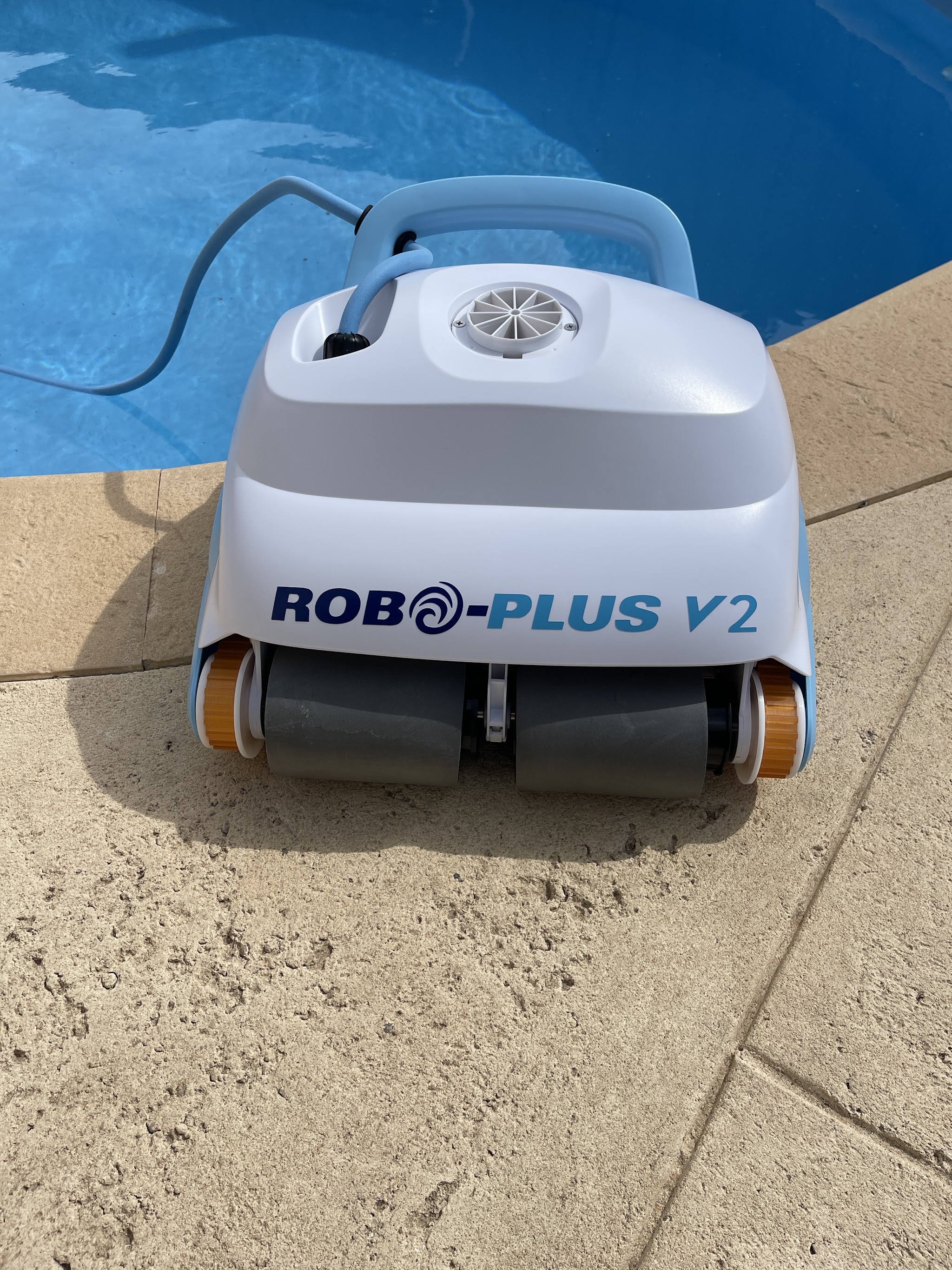 A Robo-Plus V2 robotic pool cleaner at the pool edge